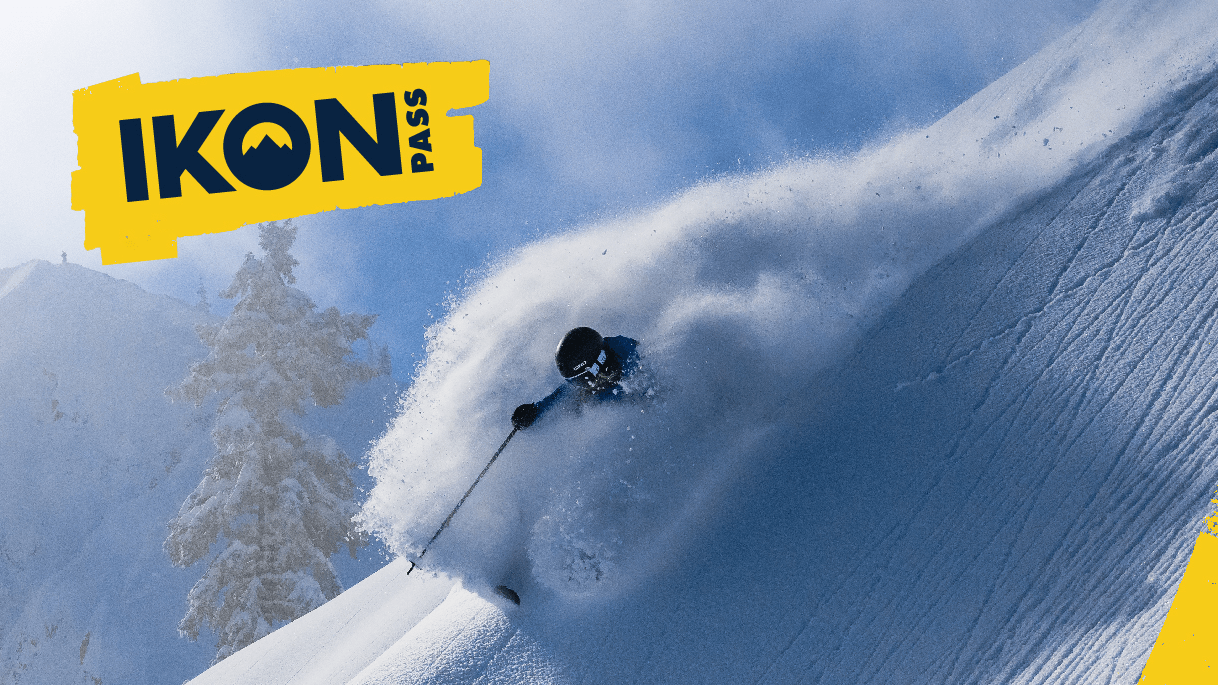 Skier in deep powder with an Ikon Pass logo on image.